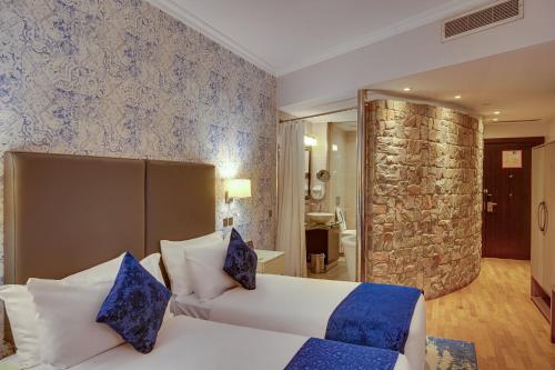 a bedroom with a white bed and a stone wall at Leola Boutique Hotel Ikeja - Lagos in Lagos