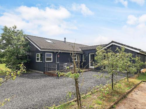a black house with a gravel driveway in front of it at 10 person holiday home in Brovst-By Traum in Brovst