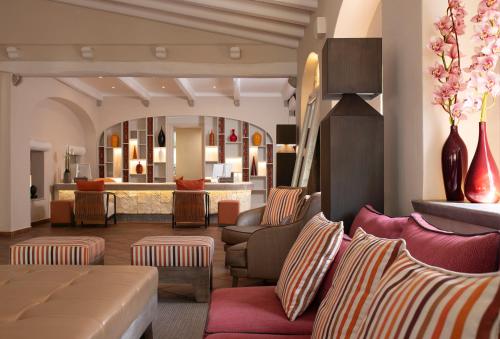 a hotel lobby with chairs and a mirror at CPH | Pevero Hotel in Porto Cervo