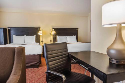 a hotel room with two beds and a desk with a chair at Comfort Inn & Suites LaGuardia Airport in Queens