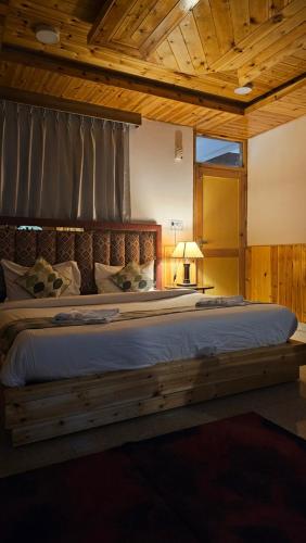 a bedroom with a large bed with a wooden headboard at Himalayan Chill House - Dragon Chowk, Old Manali with Mountain View, Balcony and Kitchen Access in Manāli