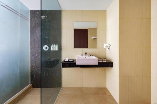 a bathroom with a sink and a glass shower at Swiss-Belhotel Makassar in Makassar