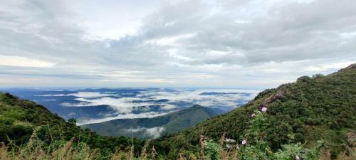 a view from the top of a mountain with clouds at Skylark Homestay Panchalimedu in Pīrmed