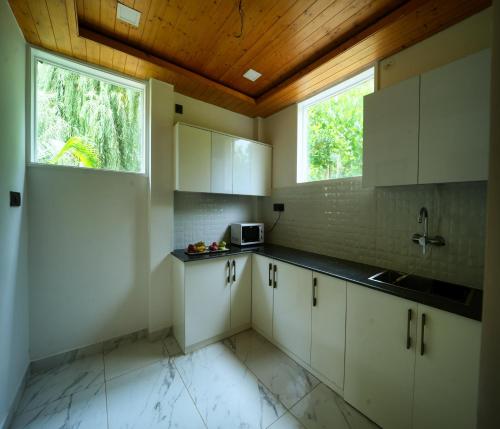 a kitchen with white cabinets and a wooden ceiling at Megha Resort & Villas, Dehradun-Where Nature Pampers You in Dehradun