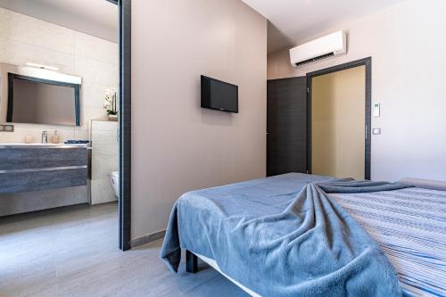 a bedroom with a bed and a mirror and a bathroom at La Villa Grazzoso - Piscine Privée in Sainte-Lucie de Porto-Vecchio