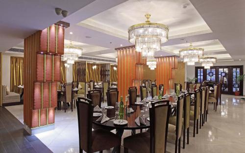 a dining room with a table and chairs and chandeliers at The Royal Phular Hotel, Muzaffarpur in Muzaffarpur