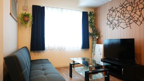 a living room with a couch and a television at Brand new mansion in Maruyama - Nekogoya Maruyama in Sapporo