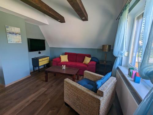 een woonkamer met een rode bank en een tafel bij Dat smucke Reethus - OG in Born