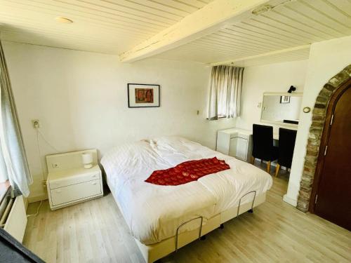 a bedroom with a bed with a red blanket on it at Farmhouse in Sint Joost with Pool & BBQ in Sint Joost
