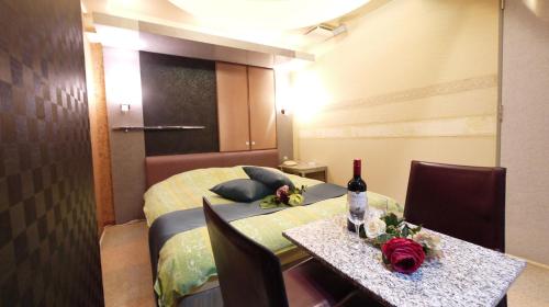 a room with a bed and a table with a bottle of wine at 井原商事ハートランド井門 in Tokyo