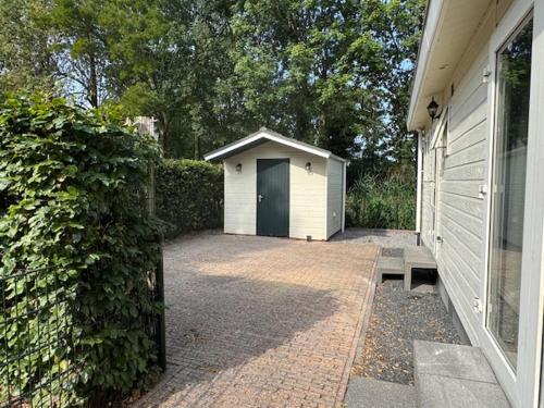 a garage with a black door next to a house at Waalrand in Ochten