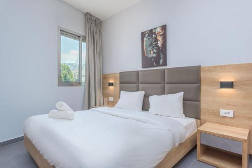 a bedroom with a large white bed and a window at Grey - Elegant Apartments in Awkar in Dbayeh