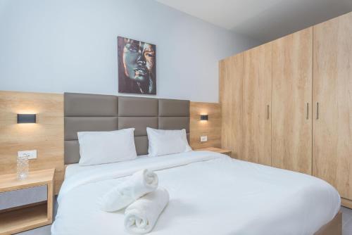 a bedroom with a large white bed with towels on it at Grey - Elegant Apartments in Awkar in Dbayeh