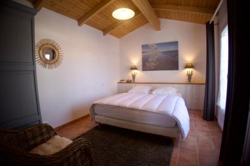 ein Schlafzimmer mit einem Bett, einem Spiegel und einem Stuhl in der Unterkunft La Galidolle, au calme à 5 minutes de la plage in La Guérinière
