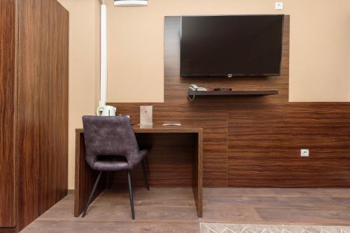 a desk with a chair and a television on a wall at Garni Hotel Zenit in Novi Sad