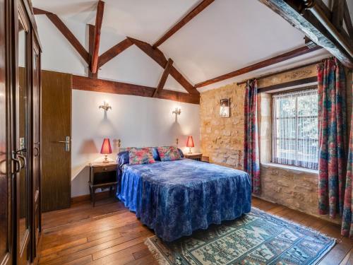 a bedroom with a blue bed and a window at Cosy holiday home with garden in Villefranche-du-Périgord