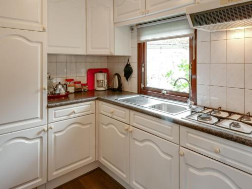 a kitchen with white cabinets and a sink and a window at Chalet in Stegeren with Pool and Gardens in Stegeren