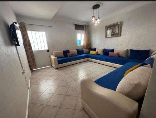 a living room with blue couches and a tv at Appartement à proximité de la plage in Martil