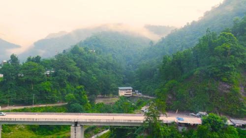 a view of a mountain with a bridge and trees at The Big Bridge- A Boutique Hotel On A Bridge in Rishīkesh