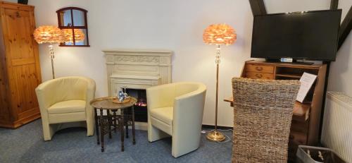 a living room with a tv and chairs and a fireplace at Landhaus Kyritz in Kyritz