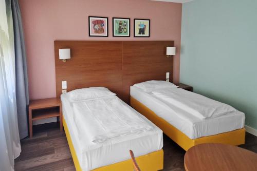 a bedroom with two beds and a wooden headboard at Garner Hotel Stuttgart City Centre in Stuttgart