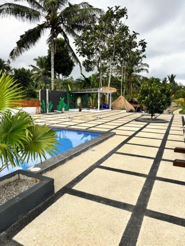 a courtyard with a pool and palm trees at Lombok Hidden Villa in Tetebatu