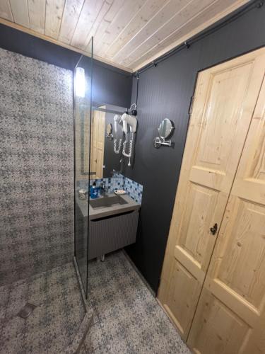 La salle de bains est pourvue d'une douche, d'un lavabo et d'une porte. dans l'établissement Eco Cottages Borjomi, à Bordjomi