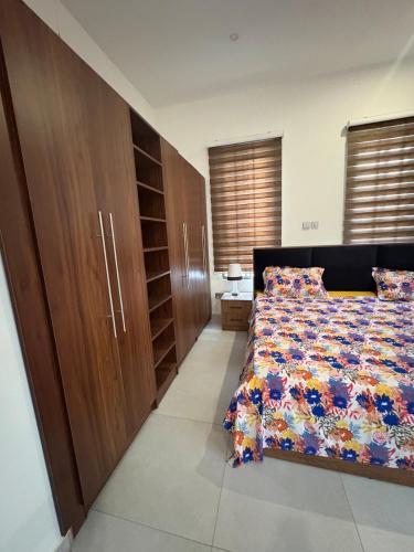 a bedroom with a bed and wooden cabinets at Emmy's 3 Bedroom Apartment in Sakumona