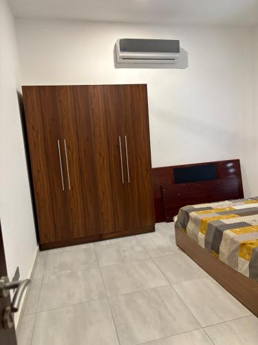 a bedroom with a bed and a wooden cabinet at Emmy's 3 Bedroom Apartment in Sakumona