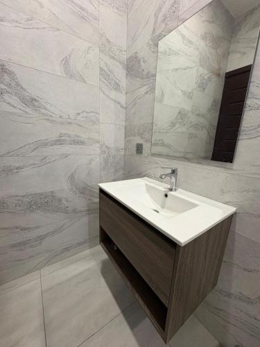 a bathroom with a sink and a mirror at Emmy's 3 Bedroom Apartment in Sakumona