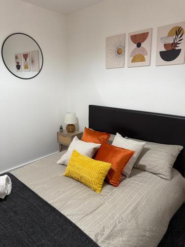 a bedroom with a bed with orange and white pillows at Luxury and Cosy Apartment near Old Trafford M16 ,Free Private Parking,Fast Wi-Fi,Self Check-In Anytime Perfect For Late Arrivals, 5 Minutes to Old Trafford Stadium in Manchester