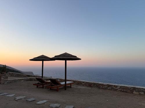 two chairs and umbrellas on a beach with the ocean at Aegean View in Artemonas
