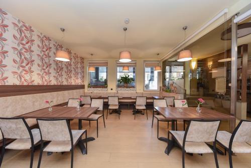 a dining room with wooden tables and chairs at Garni Hotel Zenit in Novi Sad