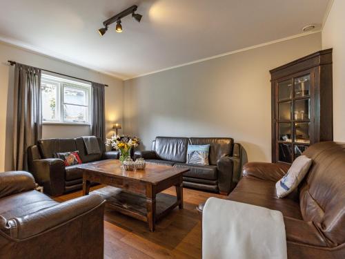 a living room with leather furniture and a table at Holiday Home in Meliskerke near Beaches in Meliskerke