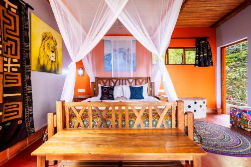a bedroom with a bed with a wooden bench at Chameleon Hill Forest Lodge in Bwindi