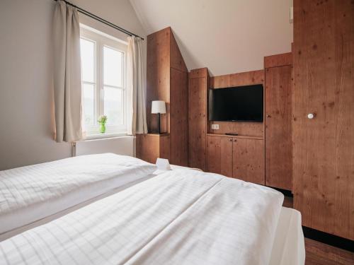 a bedroom with a white bed and a television at Semi-detached houses, turf house in Torfhaus
