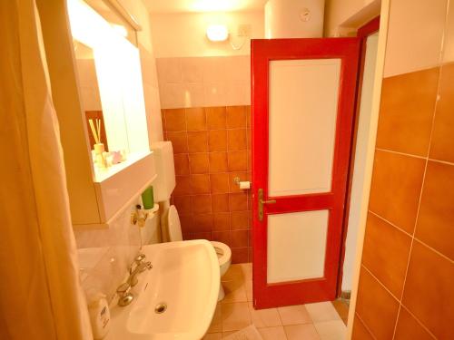 a bathroom with a white toilet and a red door at Holiday Home with Garden and shared pool in Migliorini