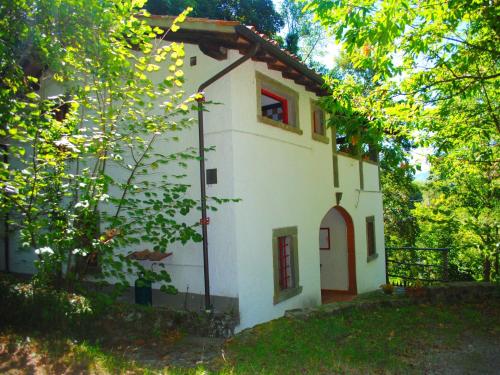 a small white house with a red window and trees at Holiday Home with Garden and shared pool in Migliorini