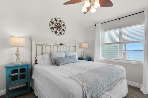 a bedroom with a bed with a ceiling fan and a window at Baywatch C10 in Pensacola Beach