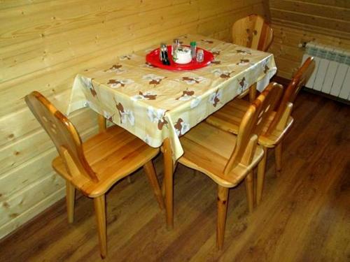 a table with four chairs and a plate of food on it at Noclegi Pod Małym Królem in Ustrzyki Dolne