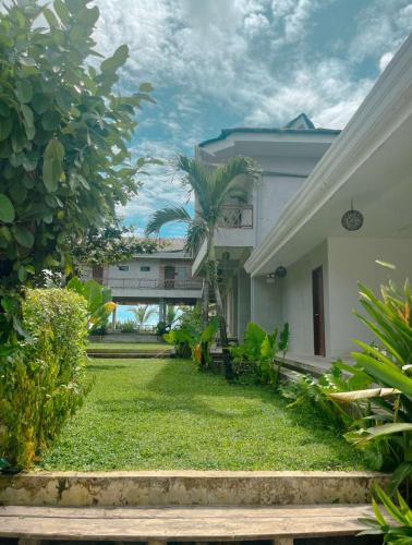 a house with a grass yard and a building at The Boardrooms in General Luna