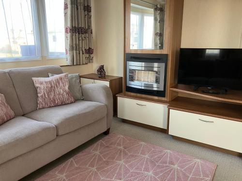 a living room with a couch and a flat screen tv at CSL Holidays in Skegness