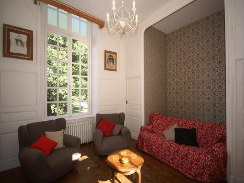 a living room with two chairs and a table and a chandelier at 18th-Century Normandy Stay in Valognes
