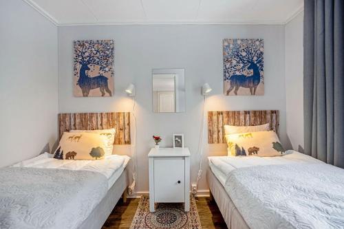 a bedroom with two beds and paintings on the wall at Woodside Home near Kungsberget in Jädraås