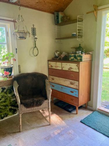a room with a dresser and a chair next to a window at Cabin in the Forest in Stillingsön