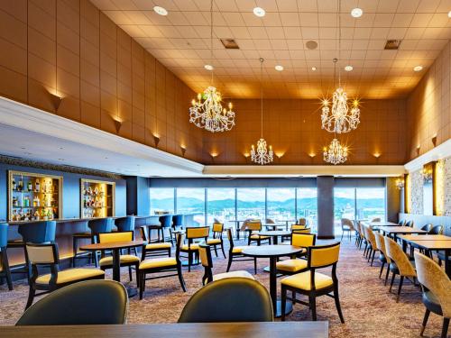 a dining room with tables and chairs and chandeliers at Hotel Nikko Himeji in Himeji