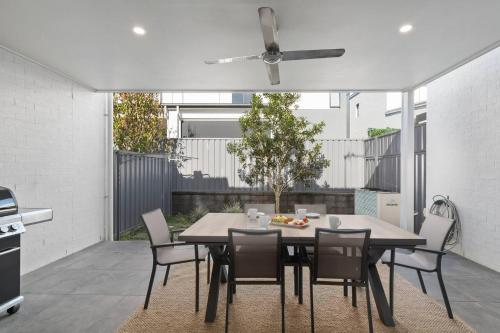 a dining room table with chairs and a ceiling fan at Brigantine Escape - Harbourside Comfort near Beach in Shellharbour