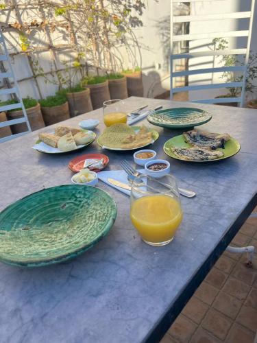 a table with plates of food and glasses of orange juice at Riad Dihya in Marrakech