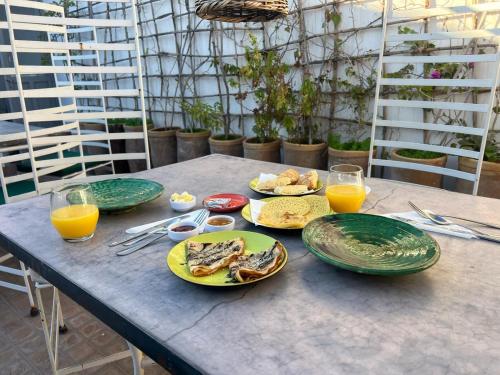 a table with plates of food and glasses of orange juice at Riad Dihya in Marrakech