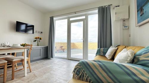 a living room with a couch and a table and a kitchen at Culfin Cottage in Gowlaun